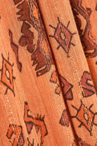 Close-up of patterned fabric with tribal designs on a peach background