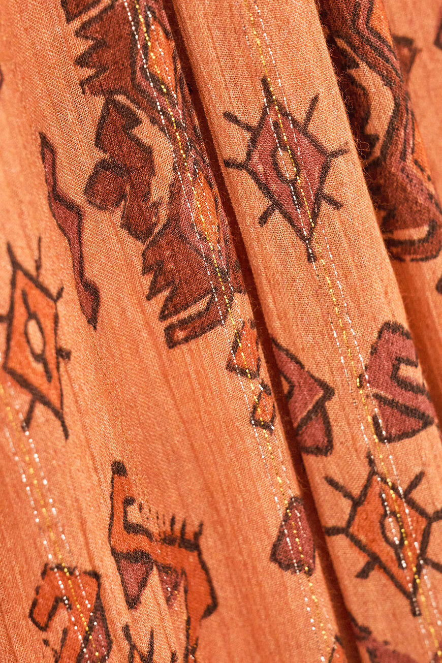 Close-up of patterned fabric with tribal designs on a peach background
