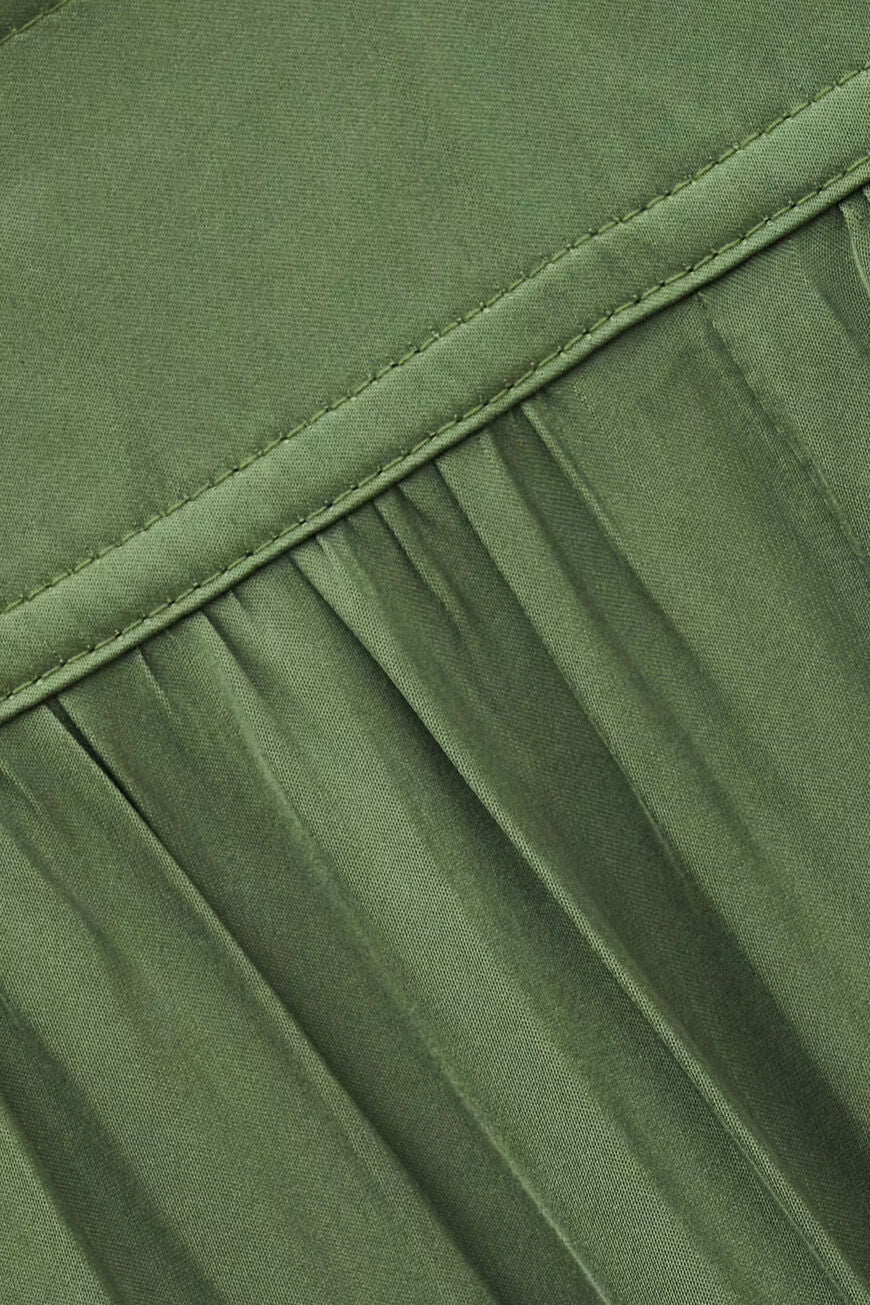 Close-up of olive green pleated fabric with a stitched seam detail.