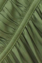 Close-up of olive green pleated fabric with diagonal stitched seams.