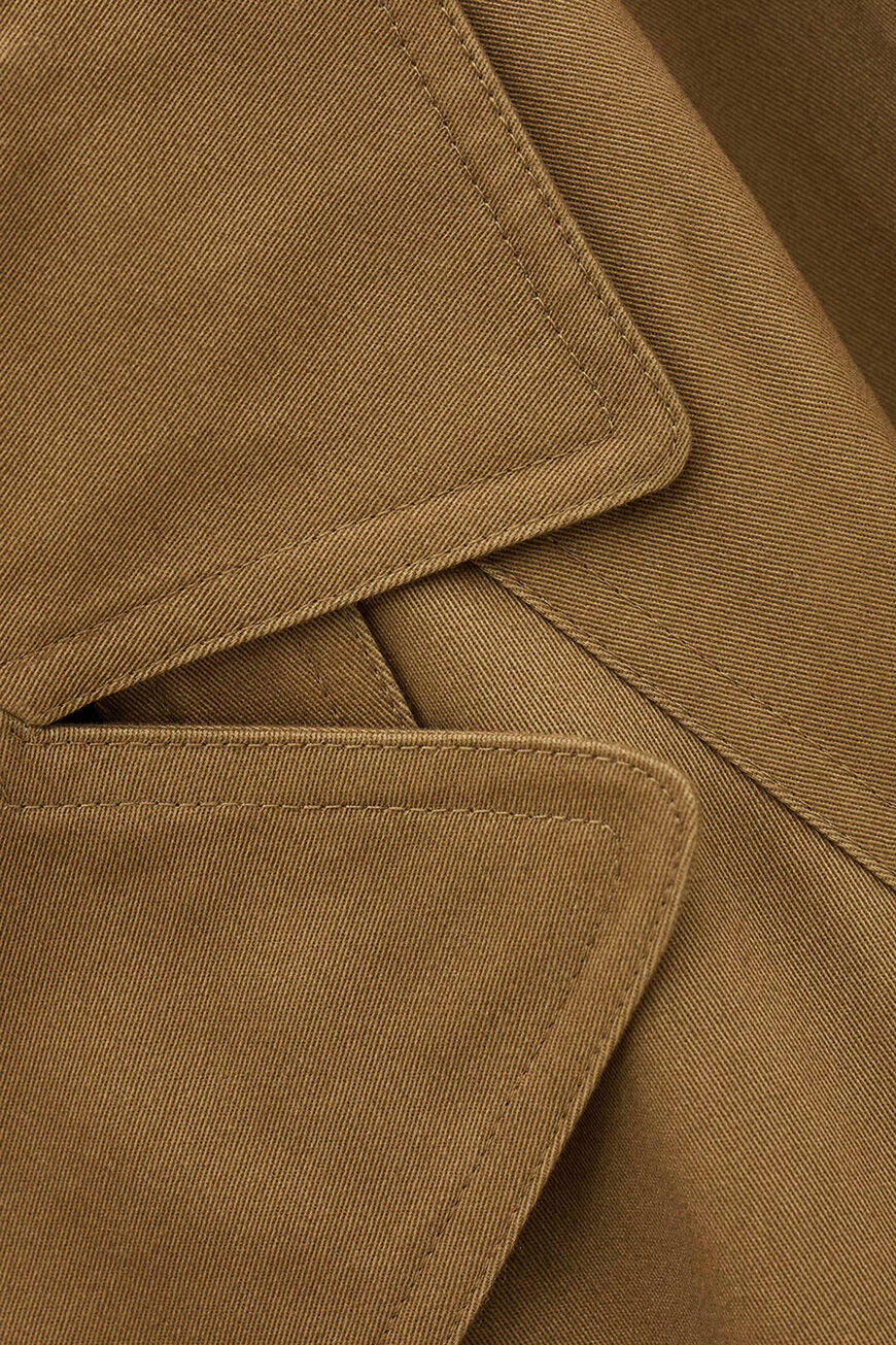 Close-up of a brown fabric garment showing the texture of the material and the details of the collar and pocket stitching.