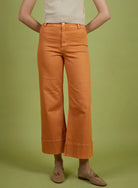 Person wearing orange pants and a light-colored top on a green background