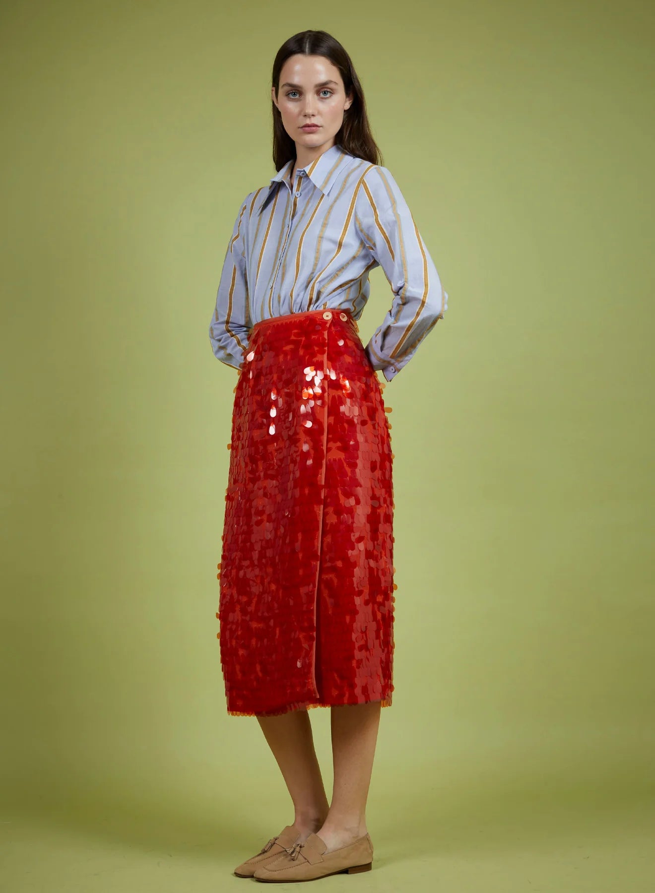 Woman wearing a red sequin skirt and striped shirt on a green background