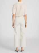 Person wearing a cream-colored blouse and striped pants on a light gray background
