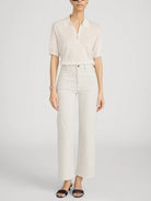 Person wearing a white blouse and striped pants on a light gray background