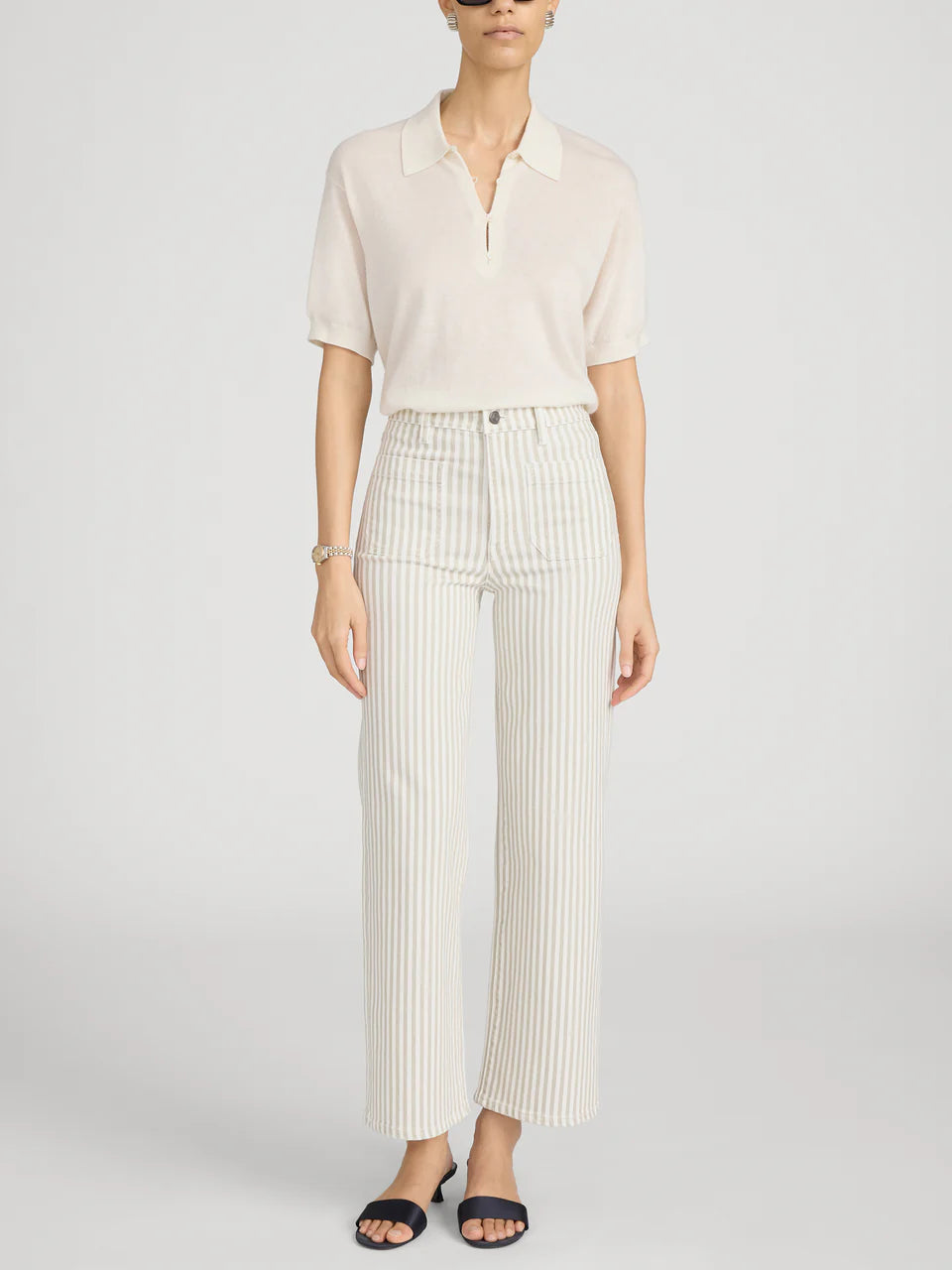 Person wearing a white blouse and striped pants on a light gray background