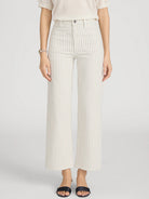Person wearing white pleated pants on a light gray background