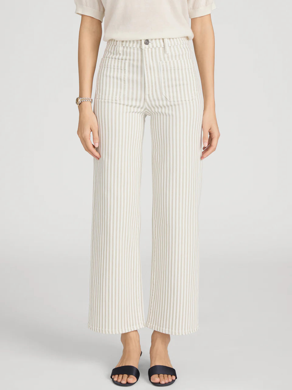 Person wearing white pleated pants on a light gray background