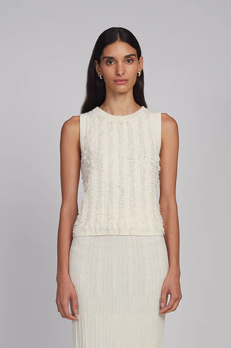 Woman wearing a white sleeveless top and skirt set against a gray background