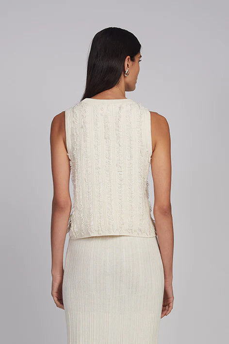 Woman wearing a cream sleeveless top and skirt set on a gray background