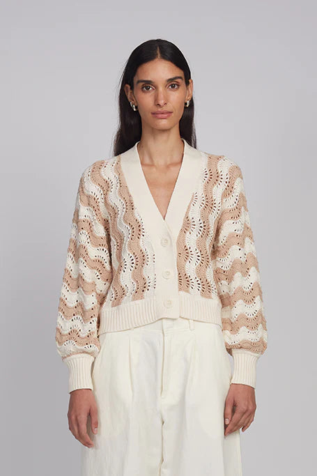 Woman wearing a patterned cardigan against a plain background