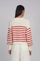 Person wearing a cream and red striped sweater on a gray background