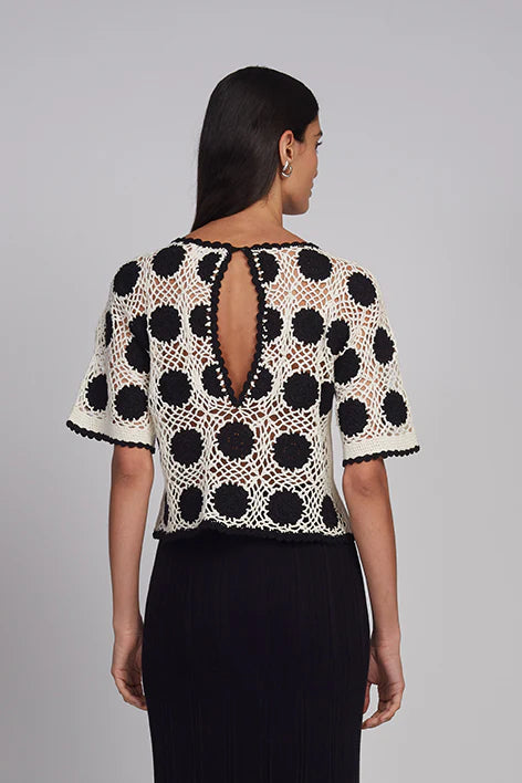 Woman wearing a black and white polka dot top with a gray background