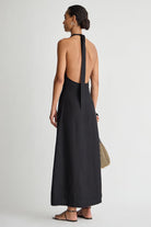 Woman wearing a black halter neck dress on a white background