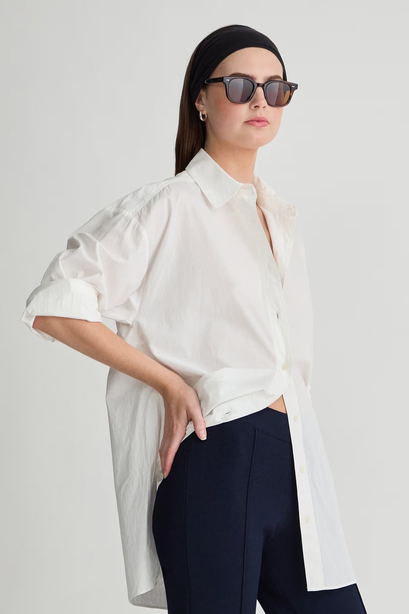 Woman wearing a white blouse and black pants against a plain background