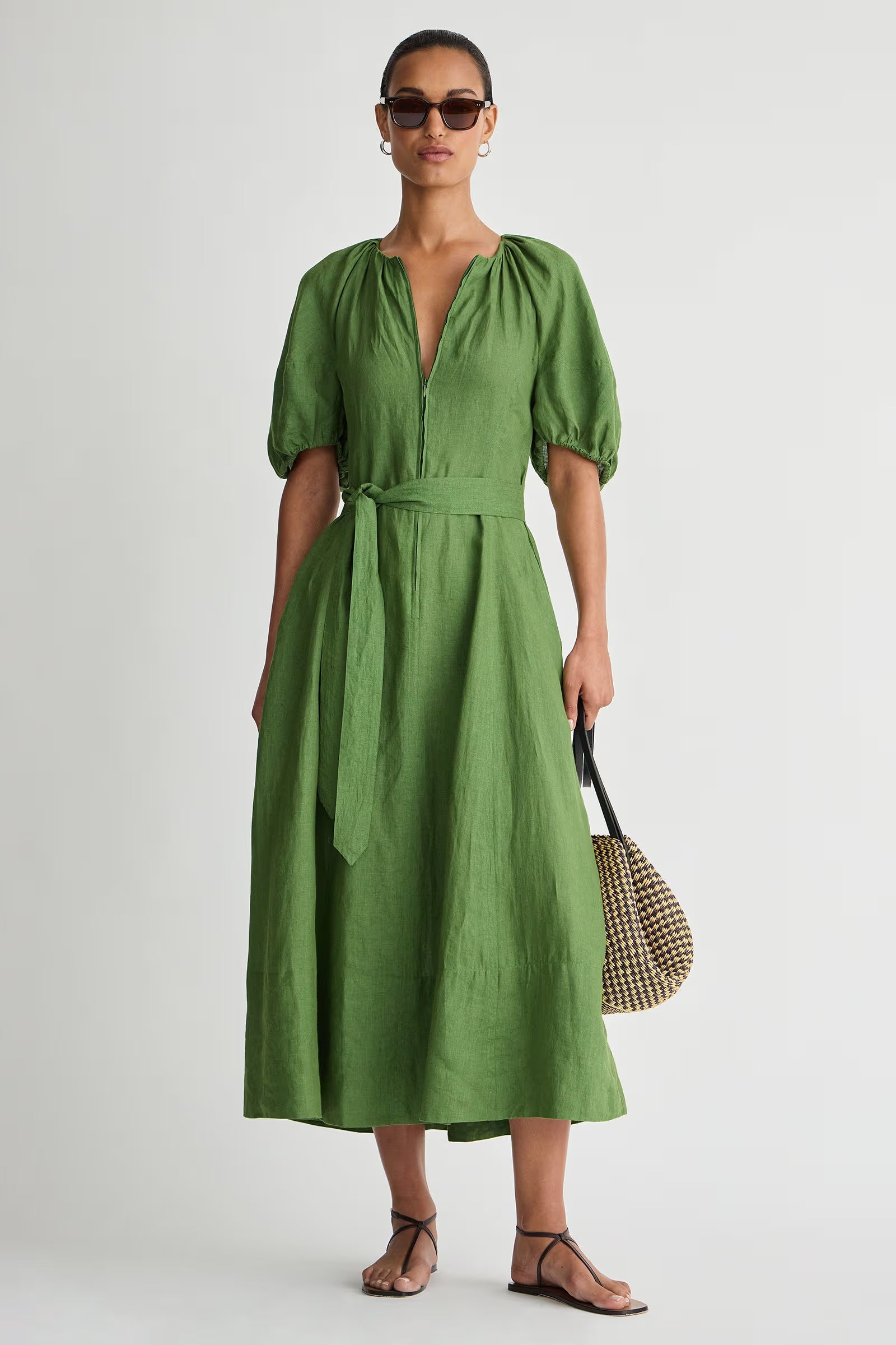 Woman wearing a green dress holding a bag against a white background