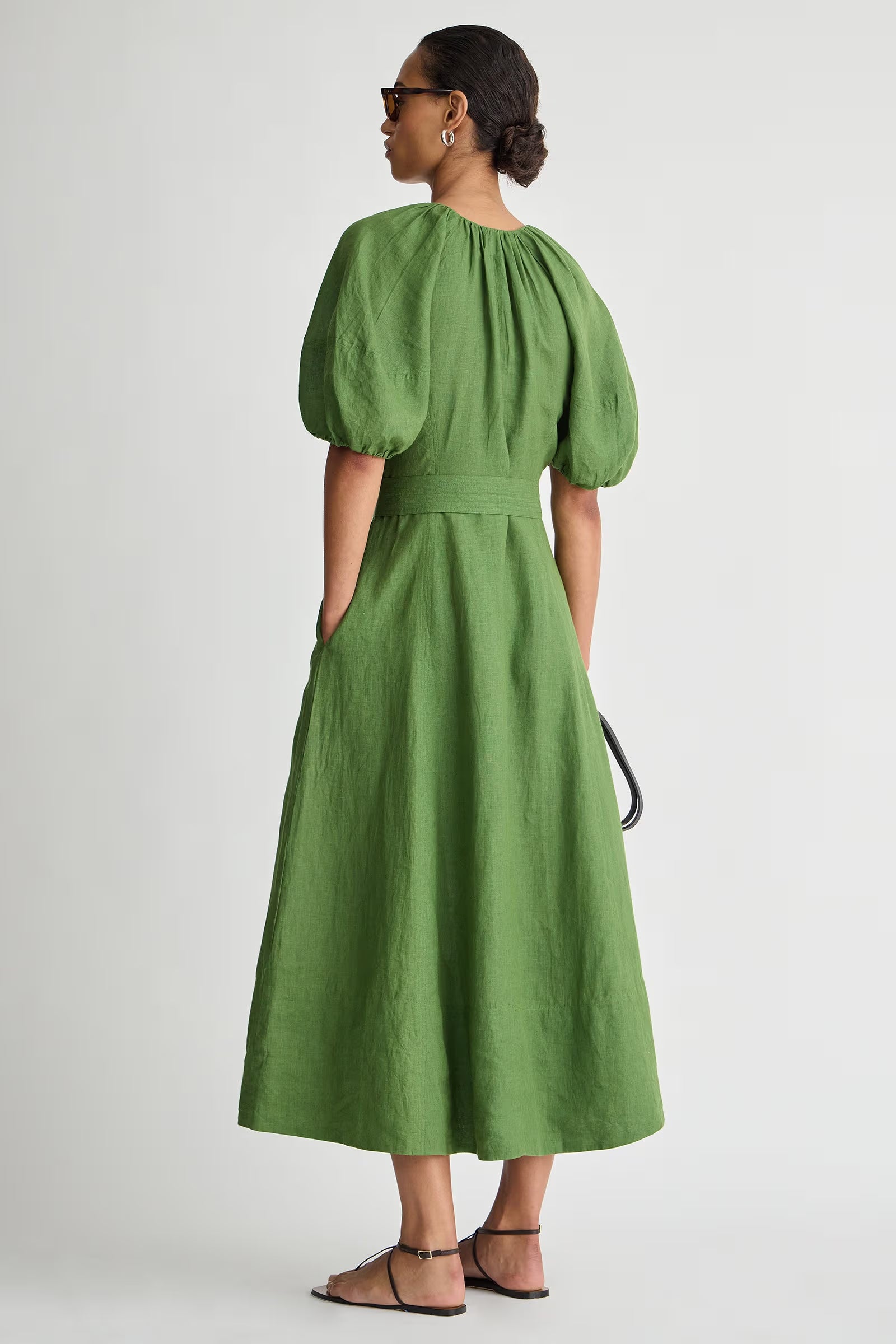 Woman wearing a green dress with puffed sleeves on a white background