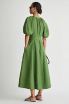 Woman wearing a green dress with puffed sleeves on a white background