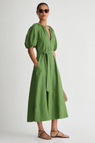 Woman wearing a green dress with puff sleeves against a white background