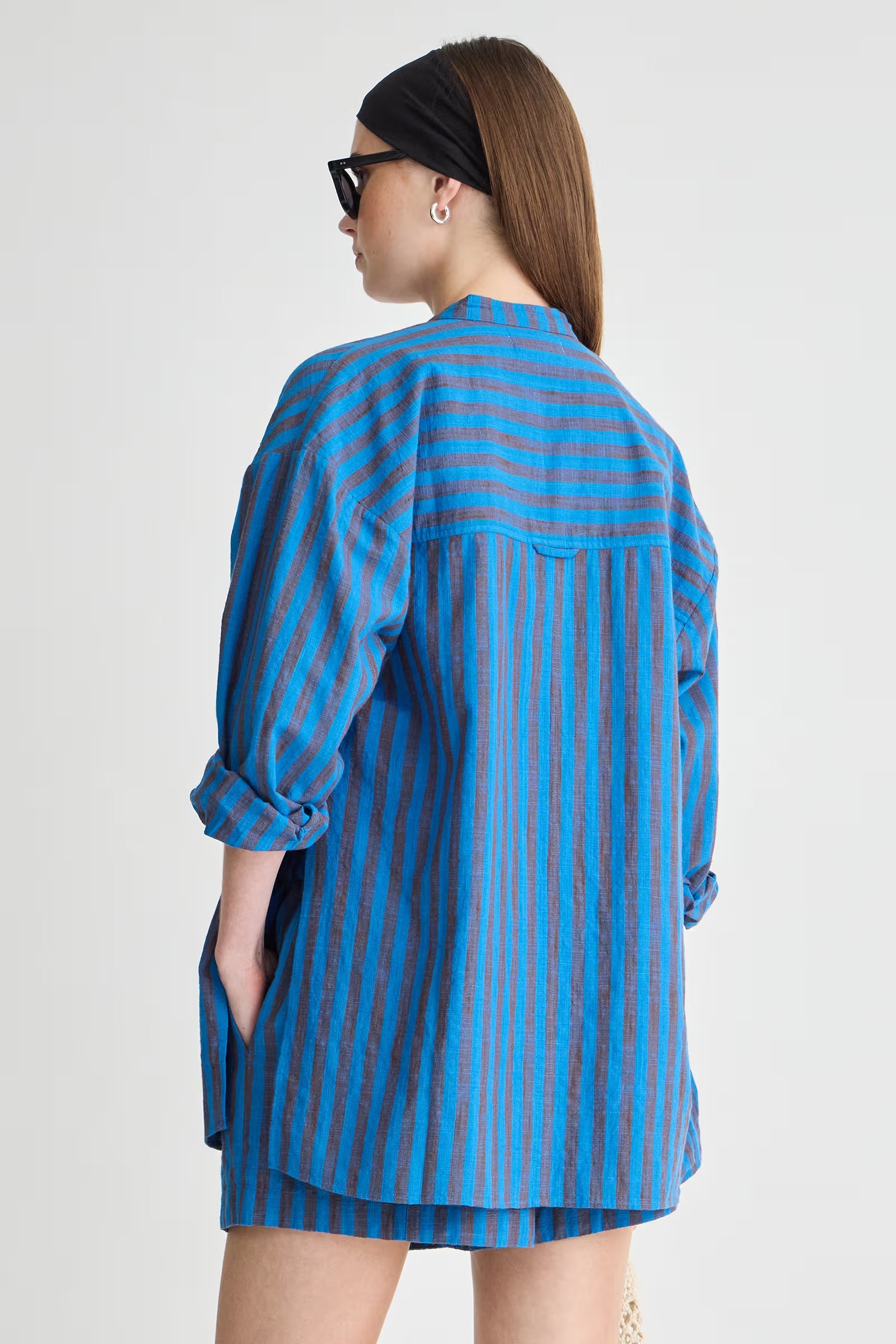 Woman wearing a blue and gray striped shirt on a white background