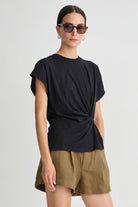 Woman wearing a black top and green shorts on a white background