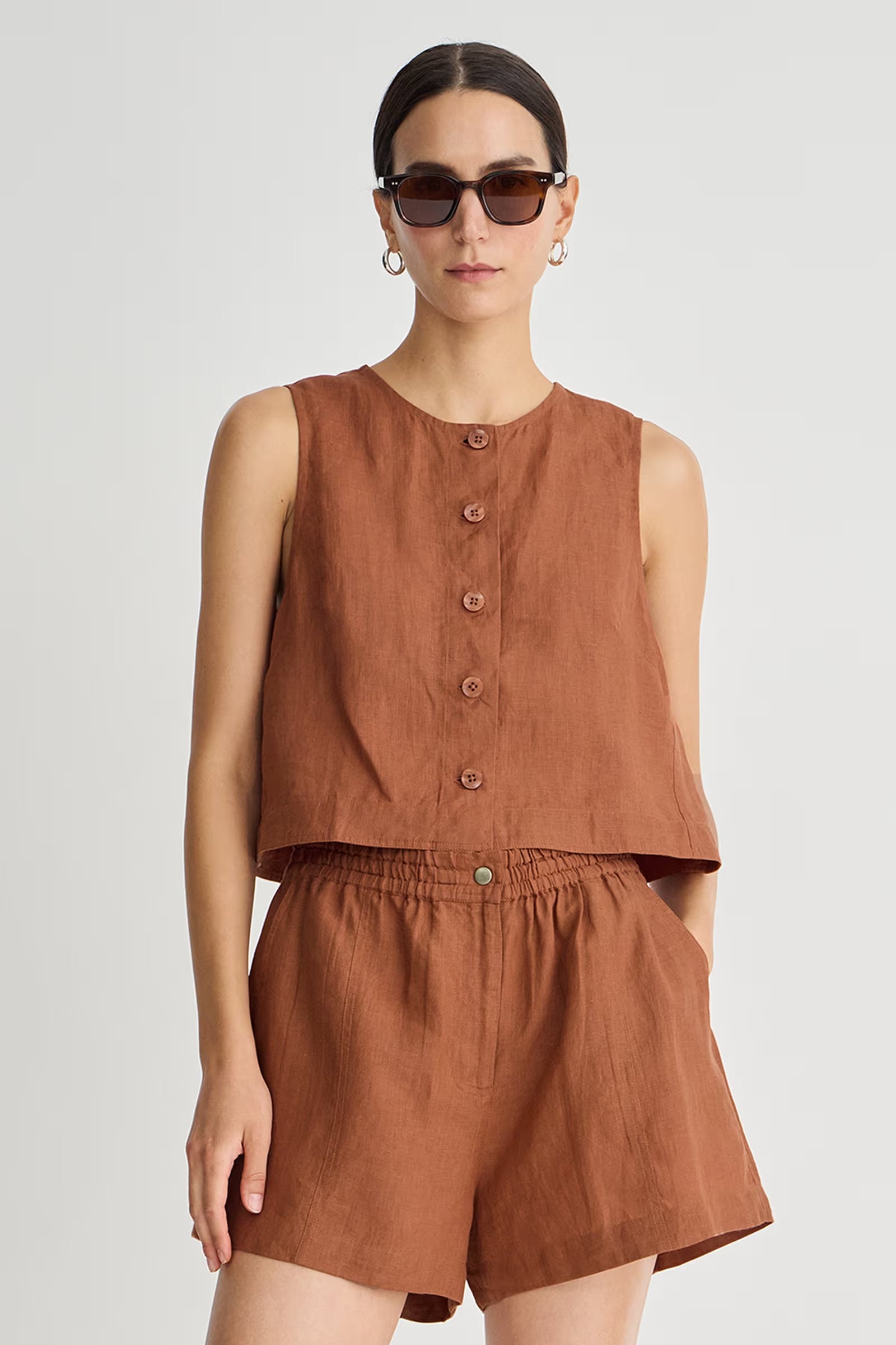 Woman wearing a brown sleeveless top and shorts set on a white background
