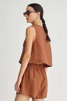 Woman wearing a brown sleeveless top and shorts set on a white background