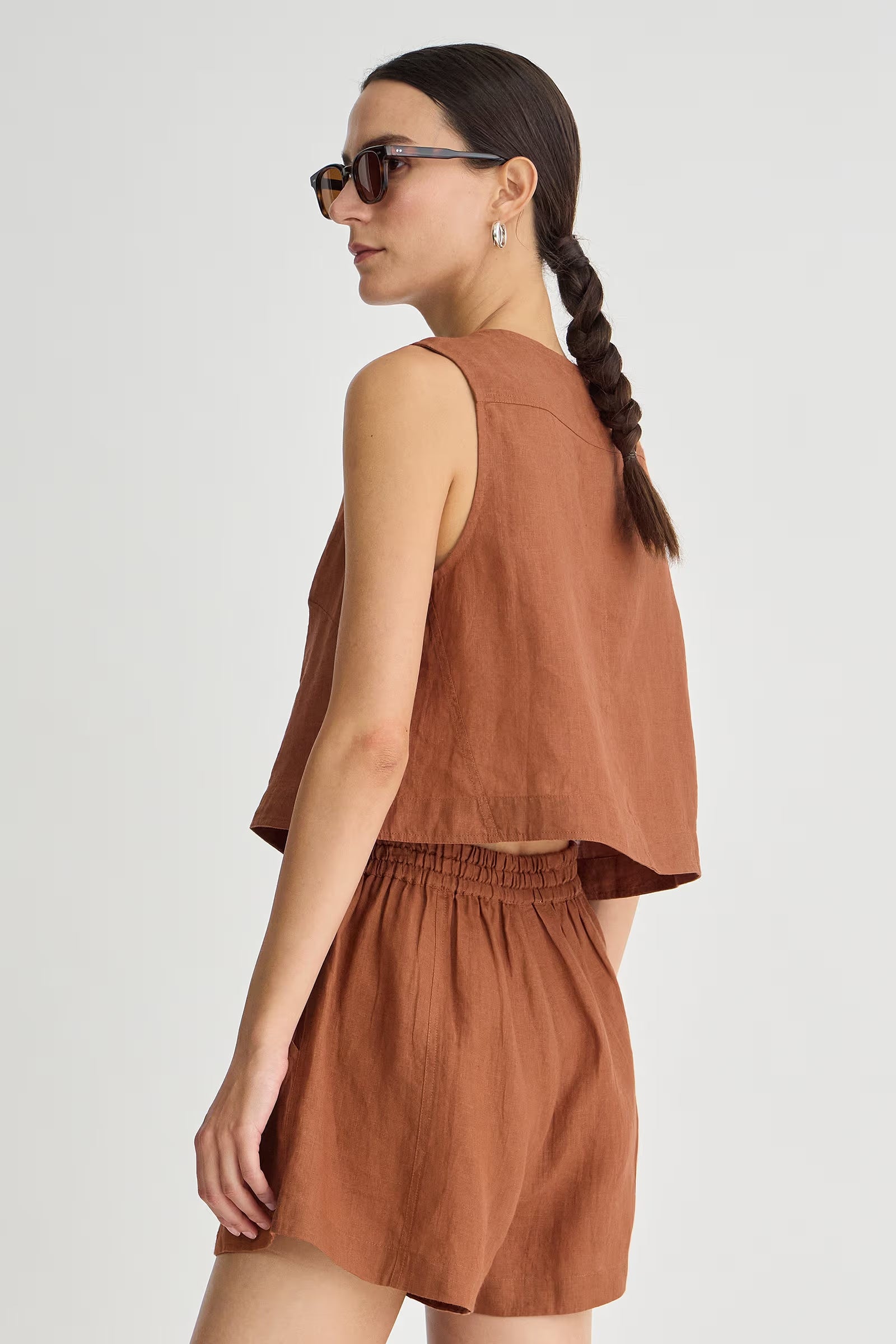 Woman wearing a brown sleeveless top and shorts set on a white background