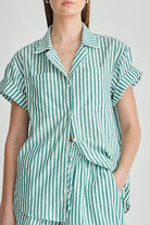 Green and white striped shirt worn by a person on a plain background