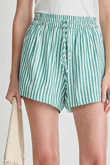 Green and white striped shorts worn by a person on a plain background