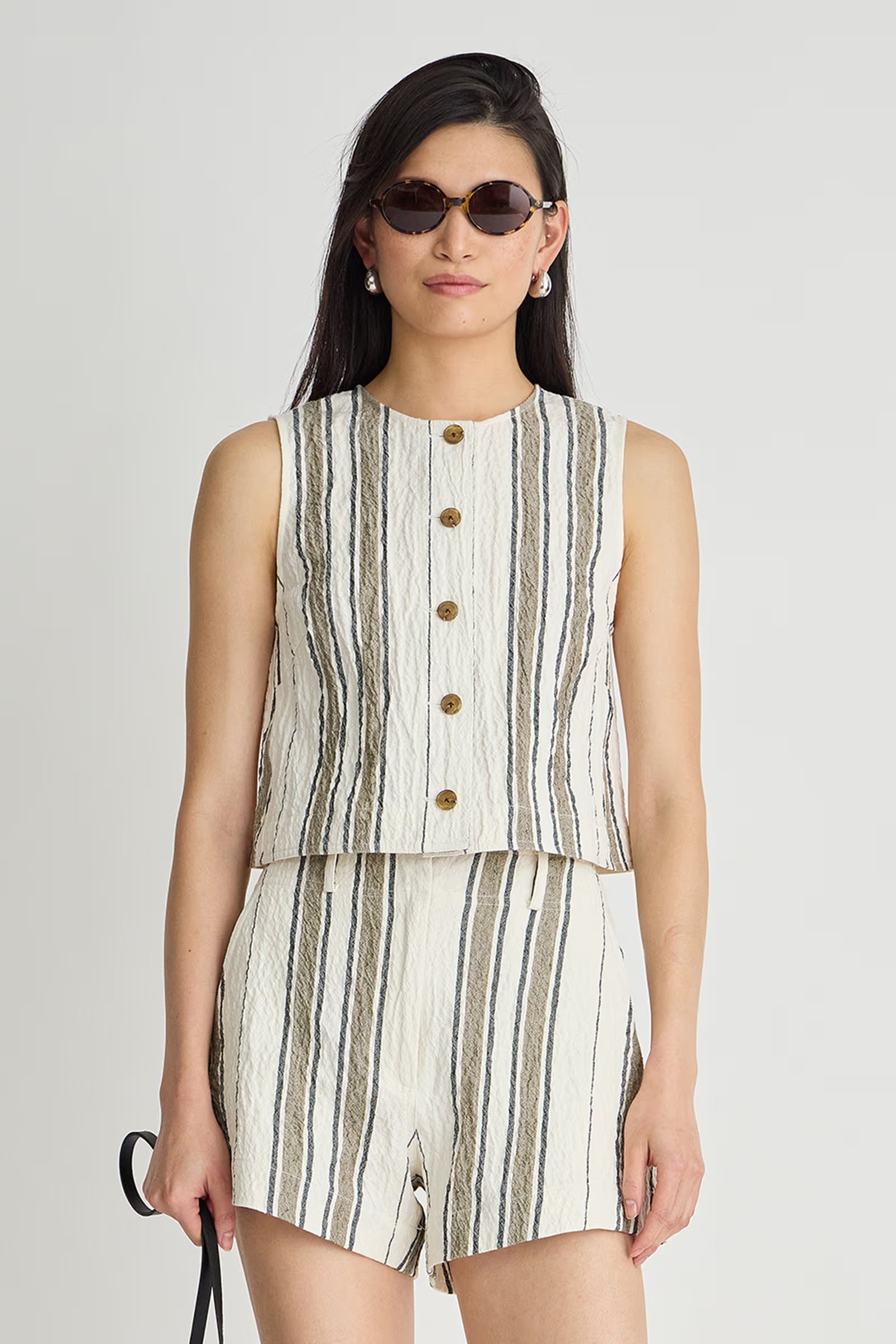Woman wearing a striped sleeveless top and shorts set on a plain background