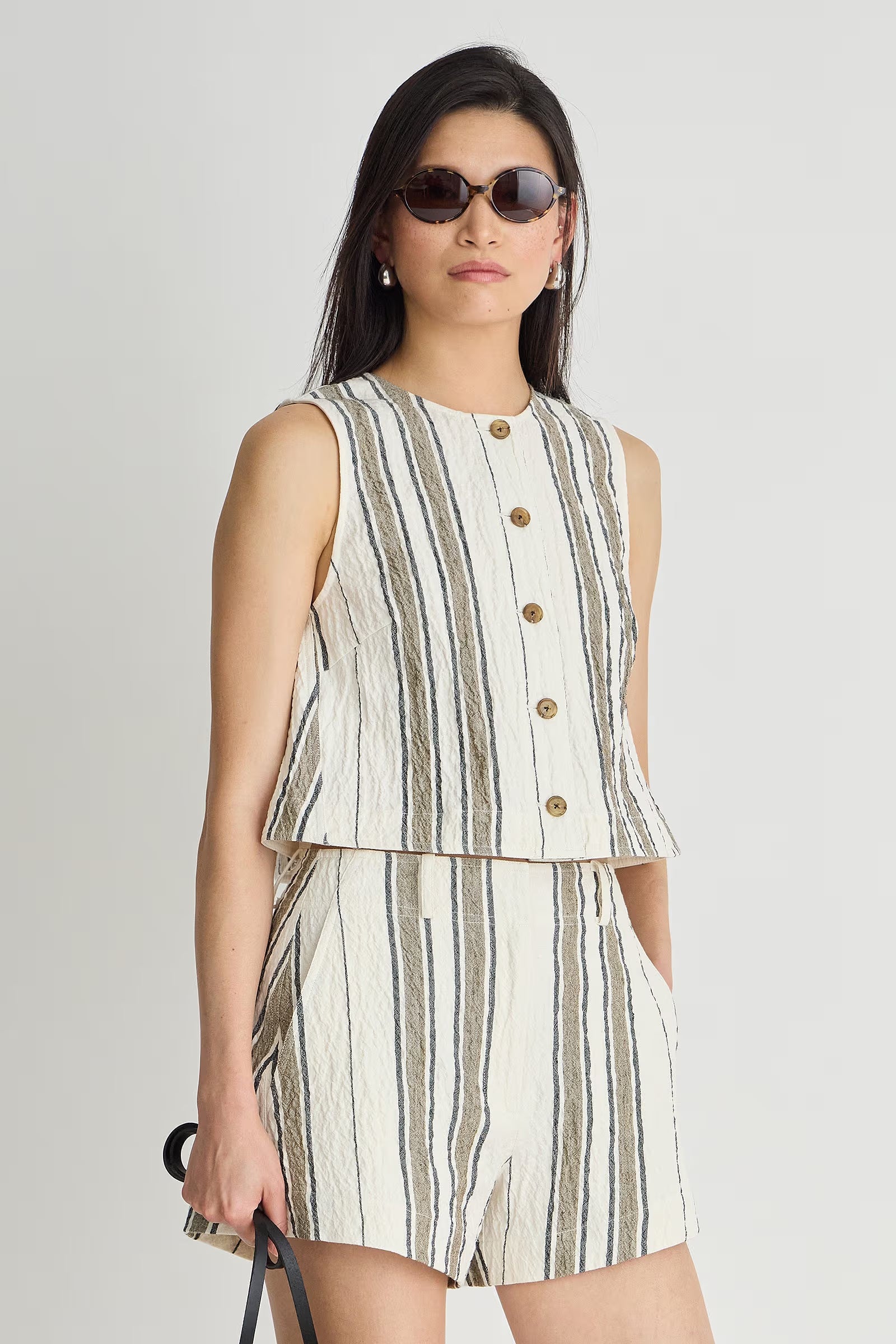Woman wearing a sleeveless striped top and shorts set on a plain background
