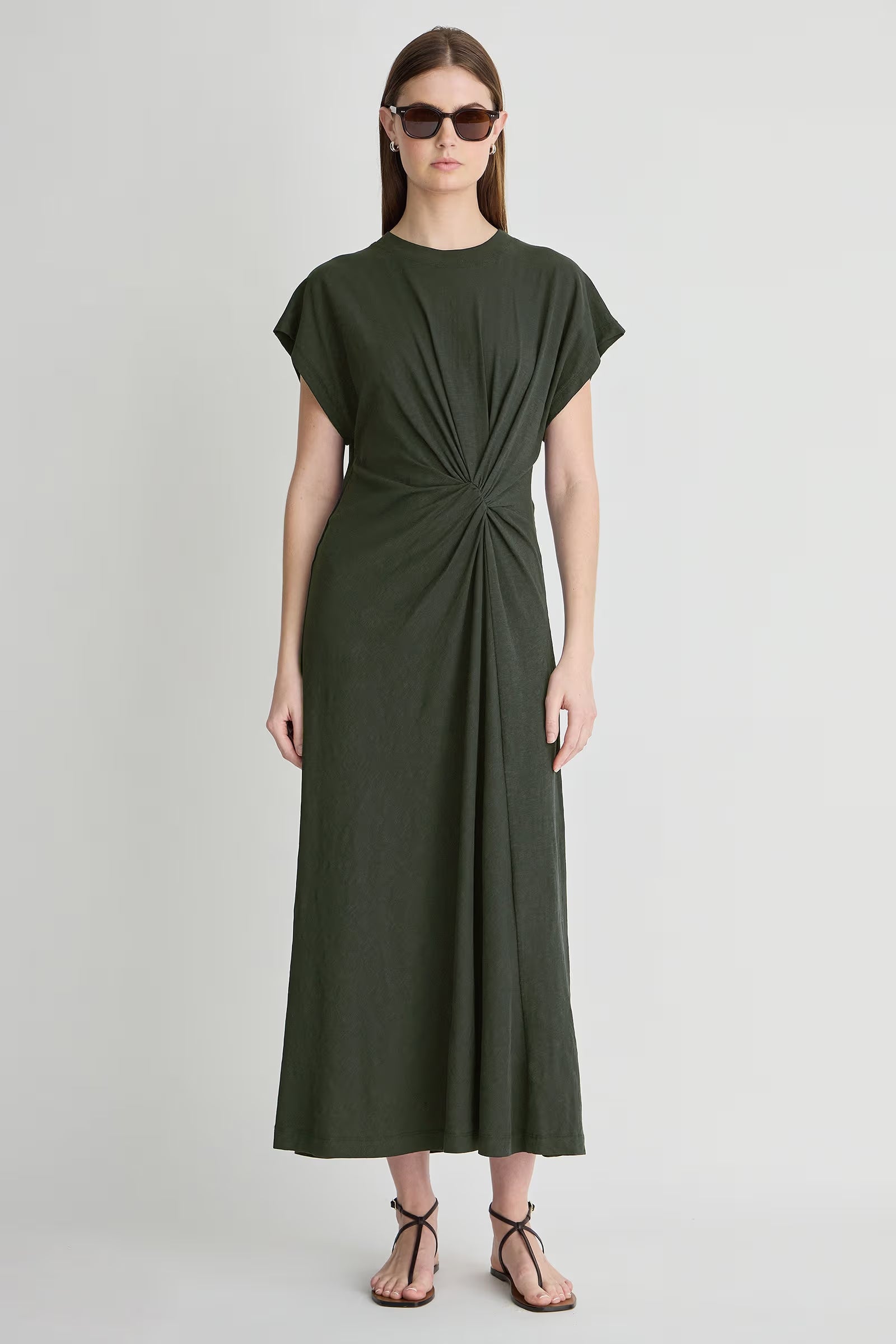 Woman wearing a green dress with a knot detail on a white background