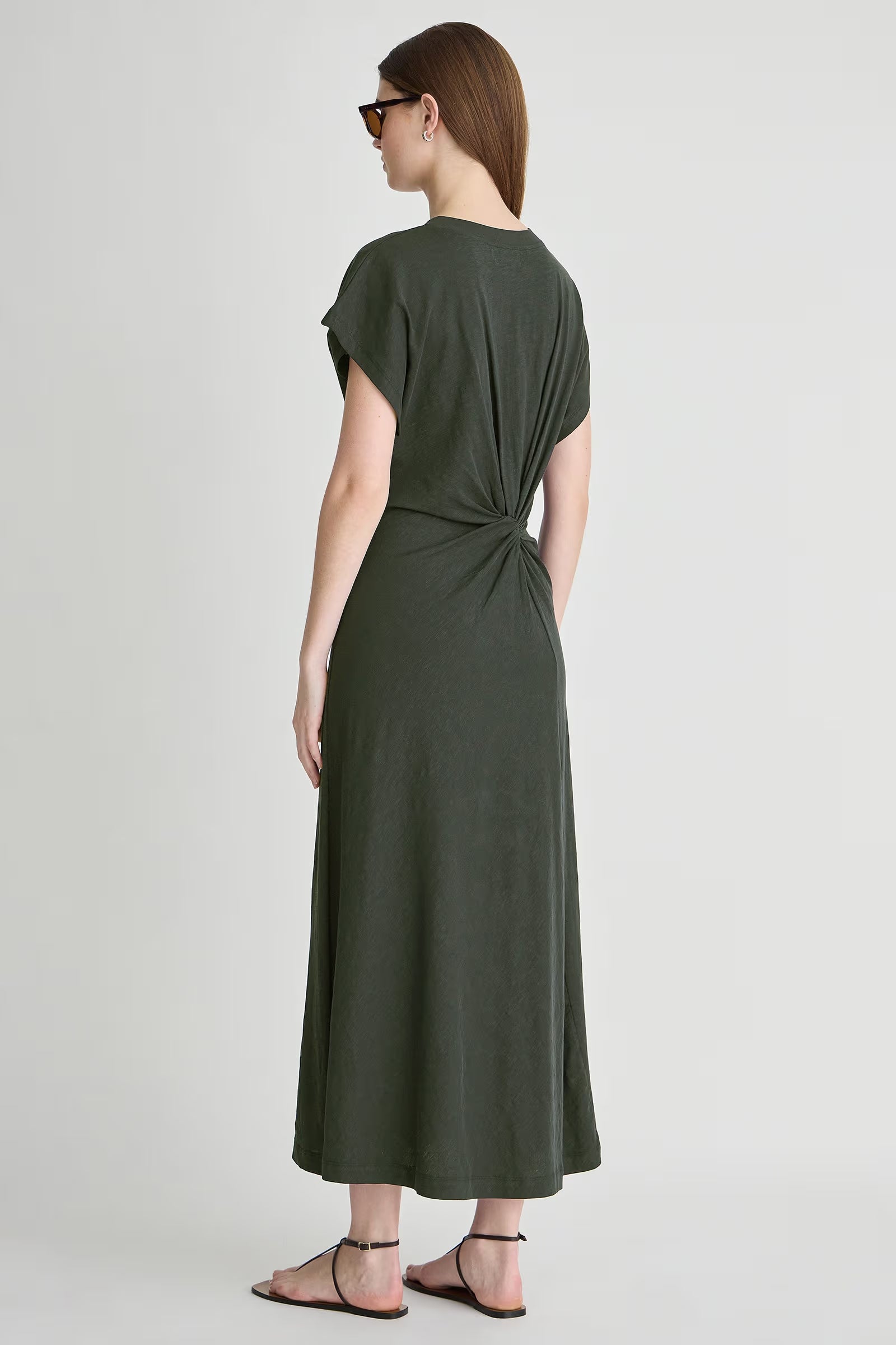 Woman wearing a green dress with a knot detail on a white background