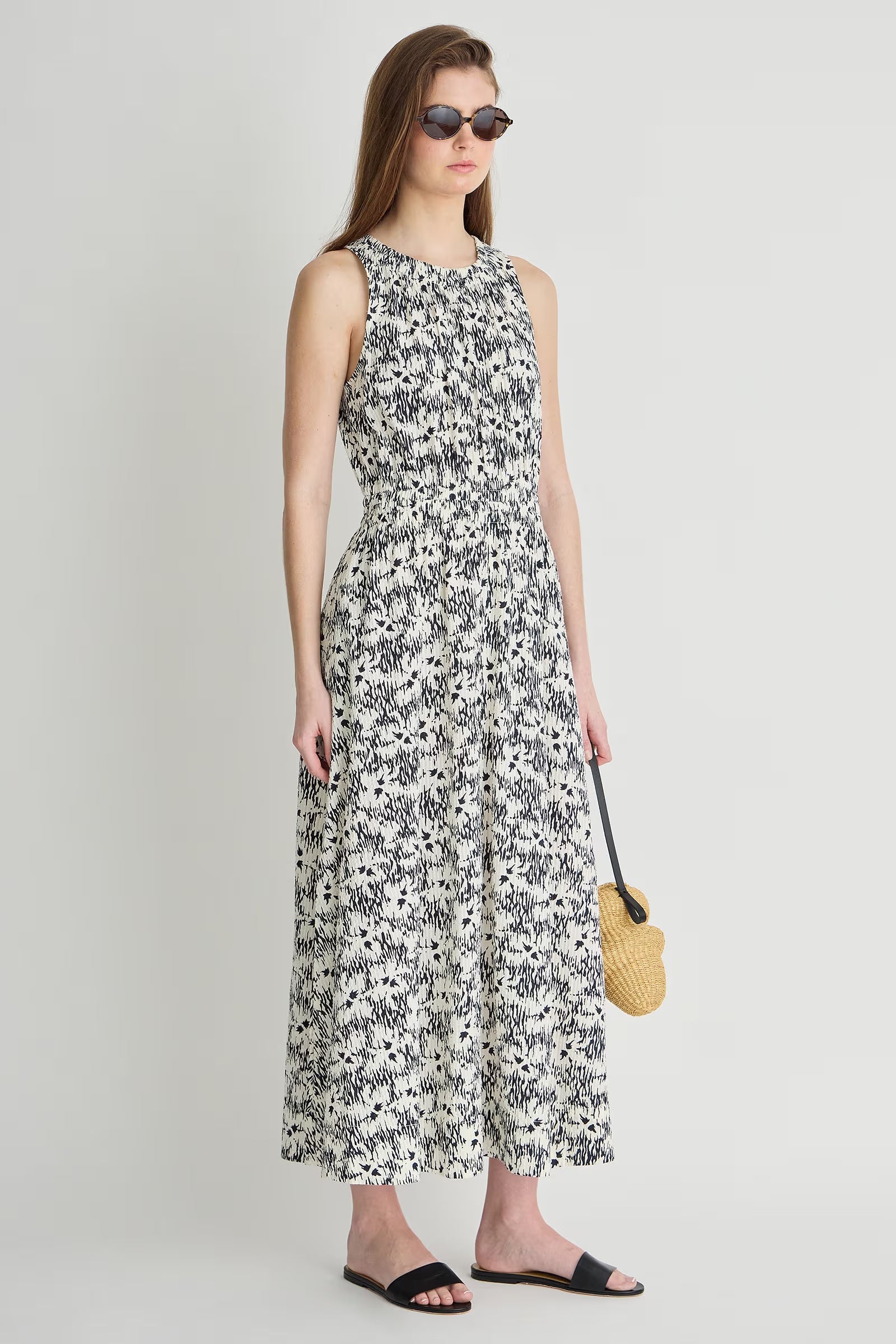 Woman wearing a floral dress holding a yellow bag on a plain background