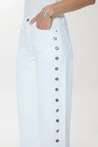White denim pants with button details on a white background