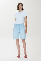 Woman wearing a white t-shirt and light blue denim shorts on a white background