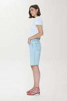 Woman wearing a light blue t-shirt and denim shorts on a white background