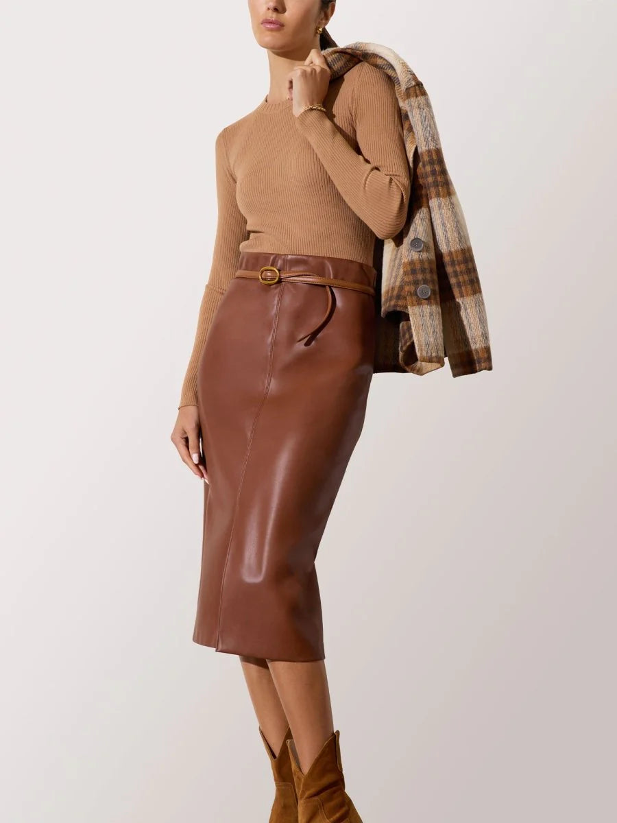 Person wearing a brown leather skirt with a beige top and plaid jacket on a white background