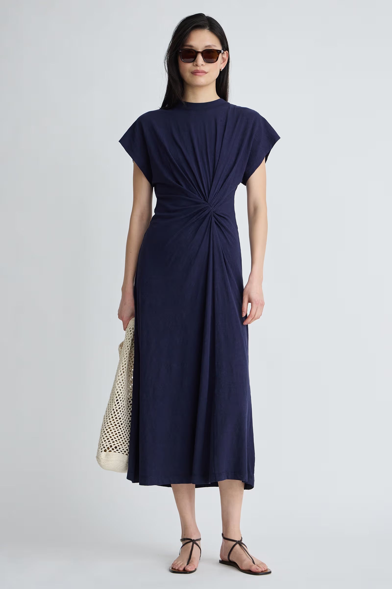 Woman wearing a navy blue dress with a knot detail on a white background