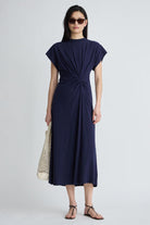 Woman wearing a navy blue dress with a knot detail on a white background