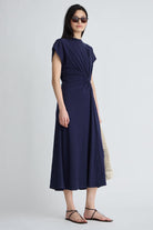 Woman wearing a navy blue dress with sunglasses on a white background