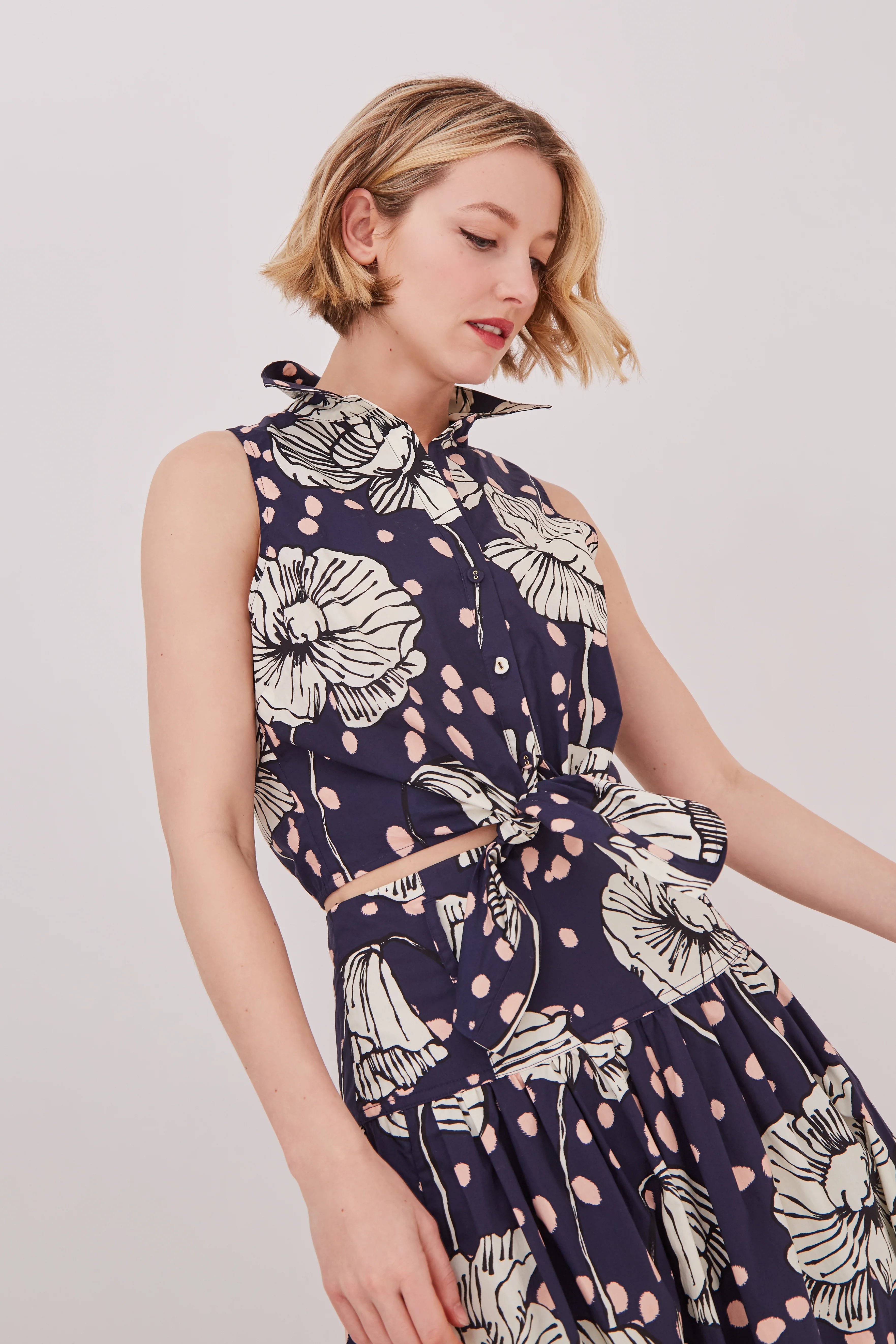 Woman wearing a navy floral dress against a plain background
