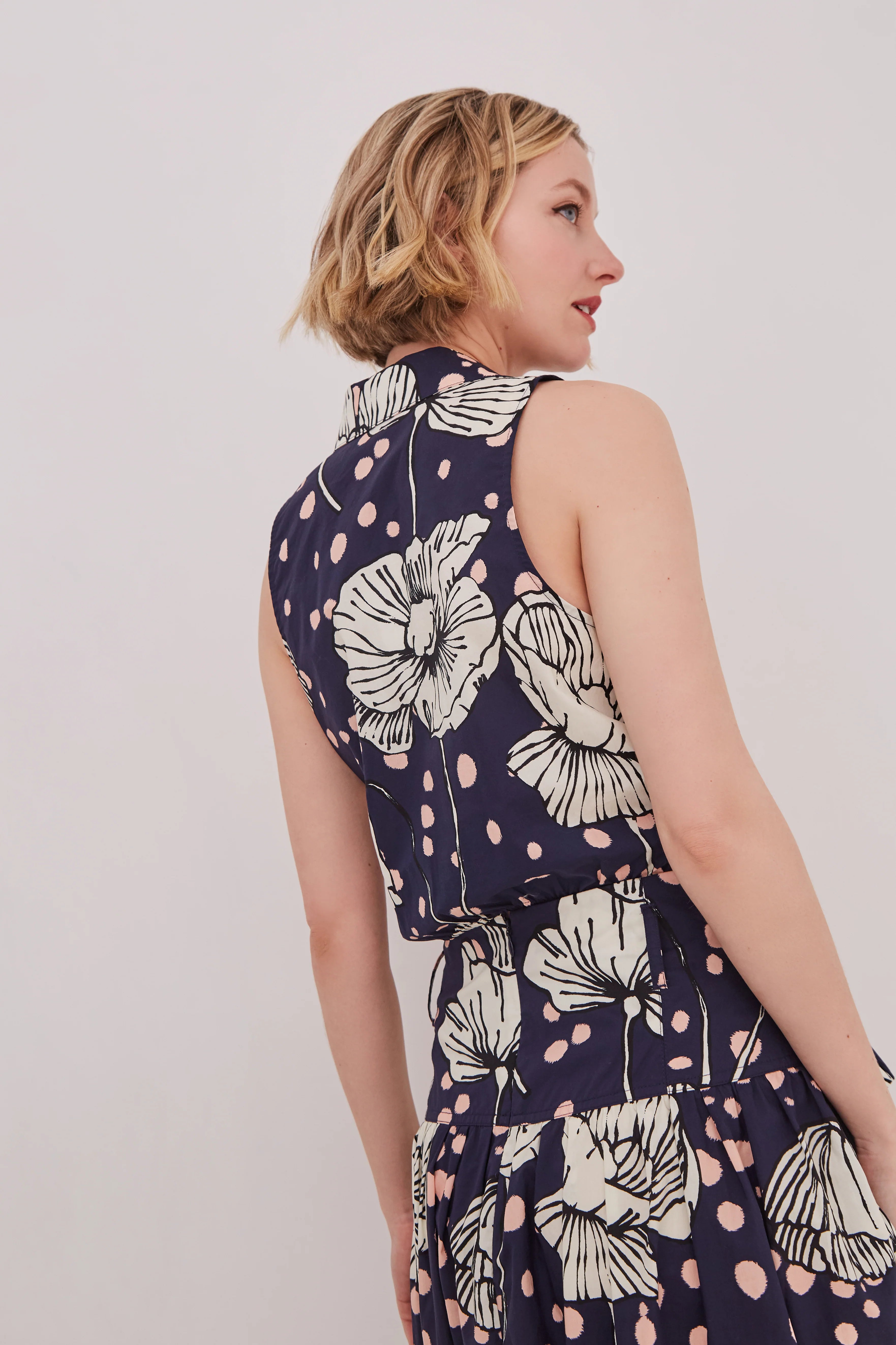 Woman wearing a navy floral dress against a plain background