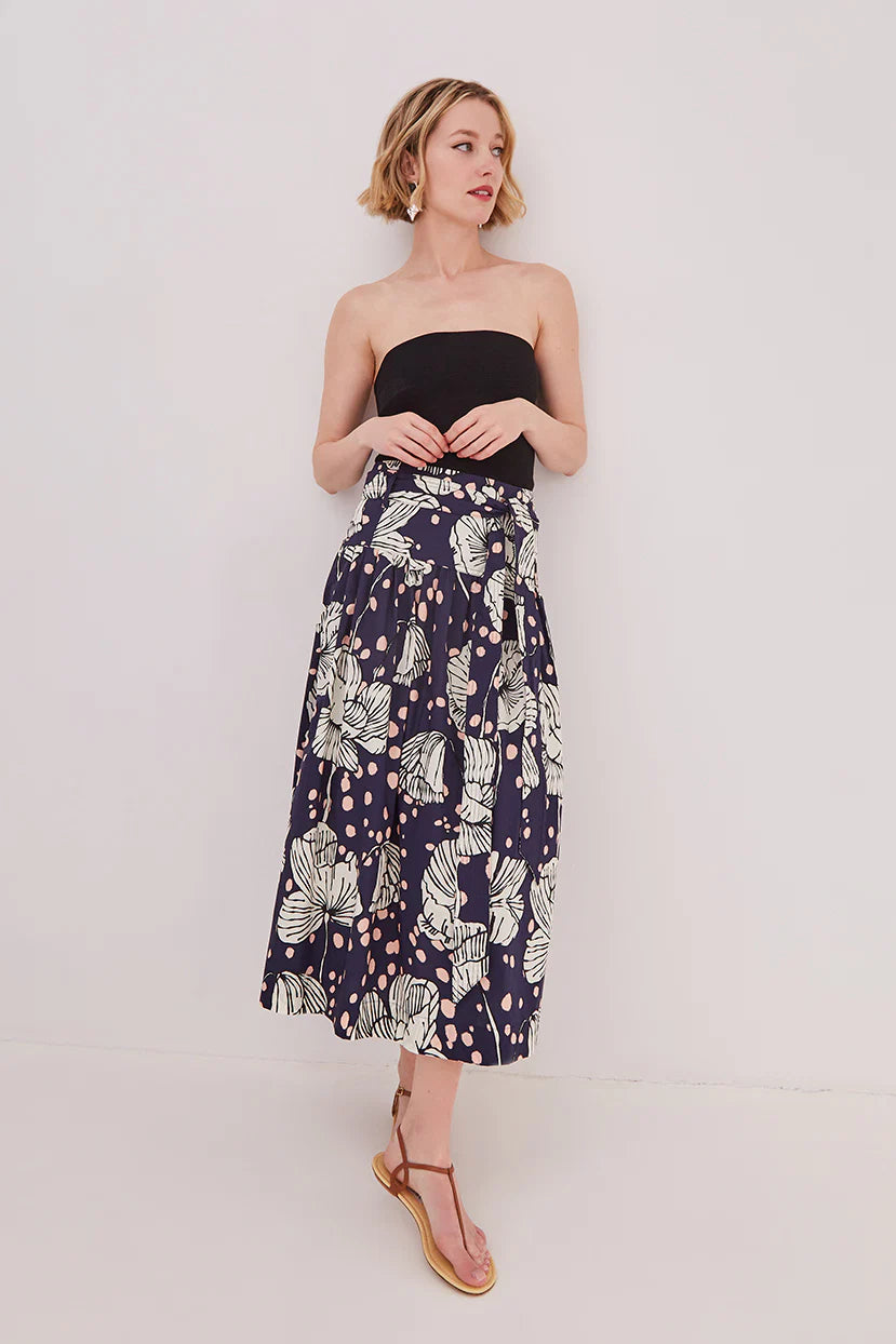 Woman wearing a strapless black top and a navy floral skirt on a white background