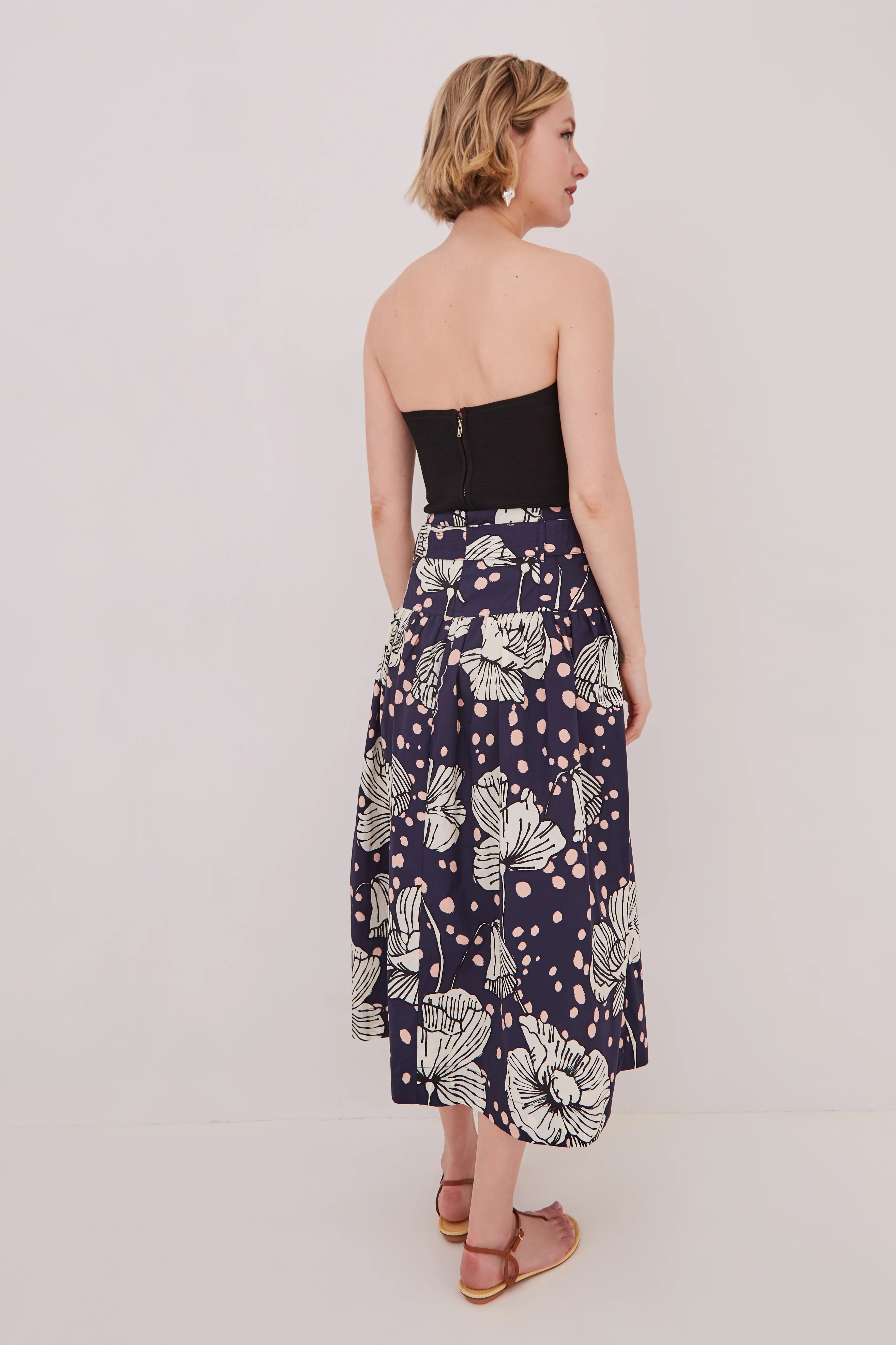 Woman wearing a strapless top and floral skirt on a white background