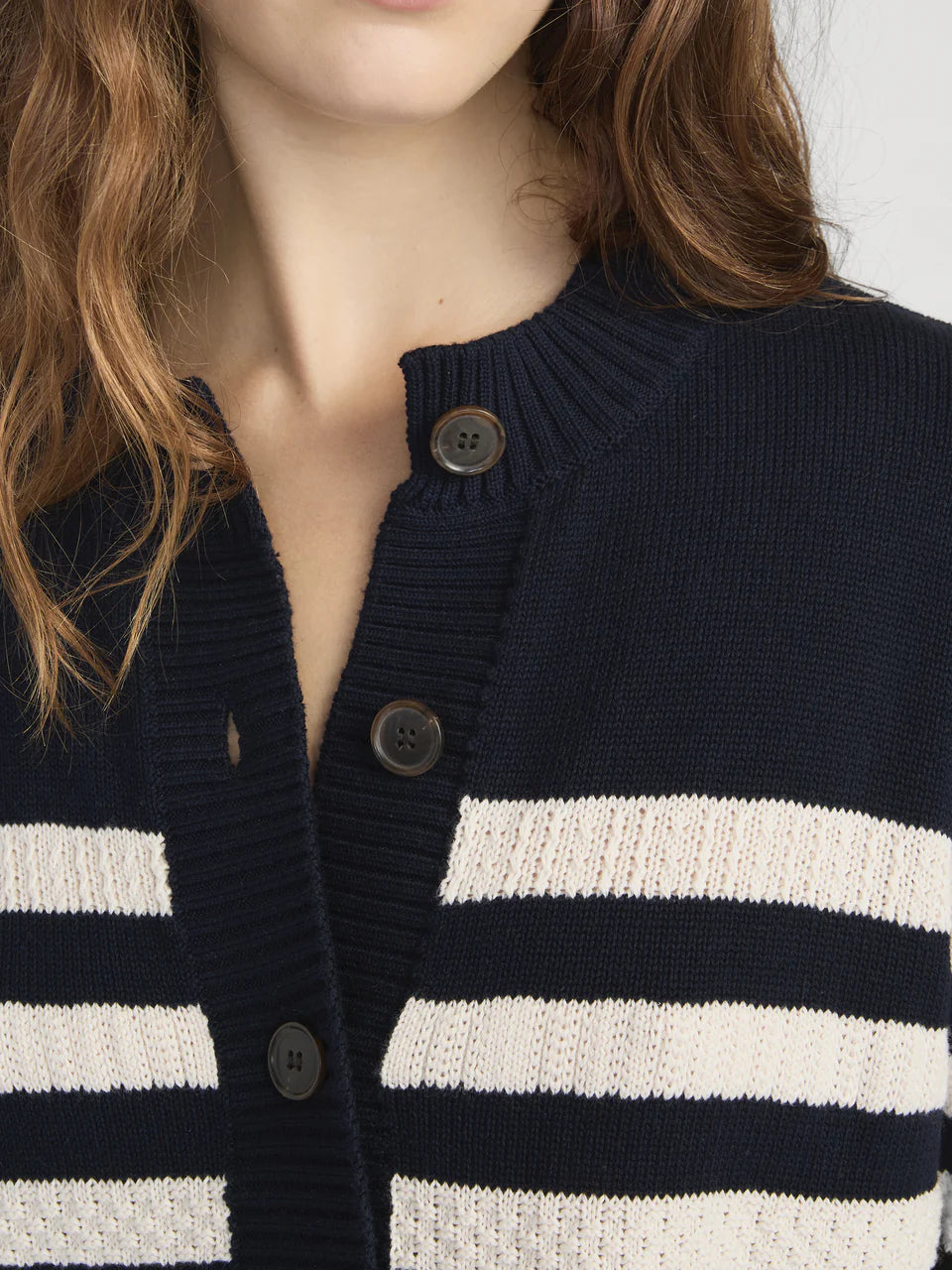 Navy and white striped cardigan with button details on a plain background
