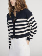 Person wearing a navy and white striped cardigan on a plain background