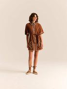 Woman wearing a brown dress with geometric patterns on a beige background