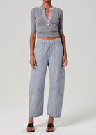 Person wearing a gray cropped top and wide-leg pants on a white background